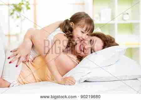 拥抱和亲吻在床上的母亲和孩子
